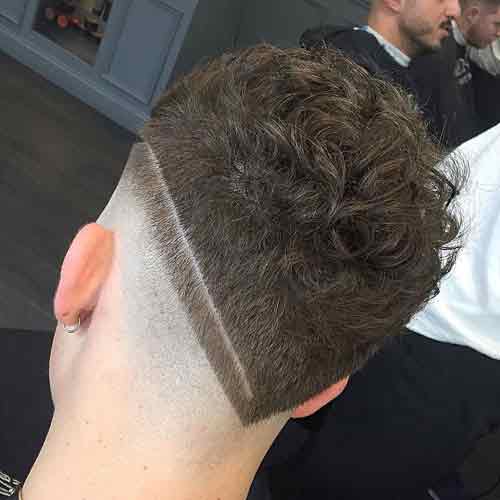 peinado con pelo rizado corto diseñado en v y skin fade