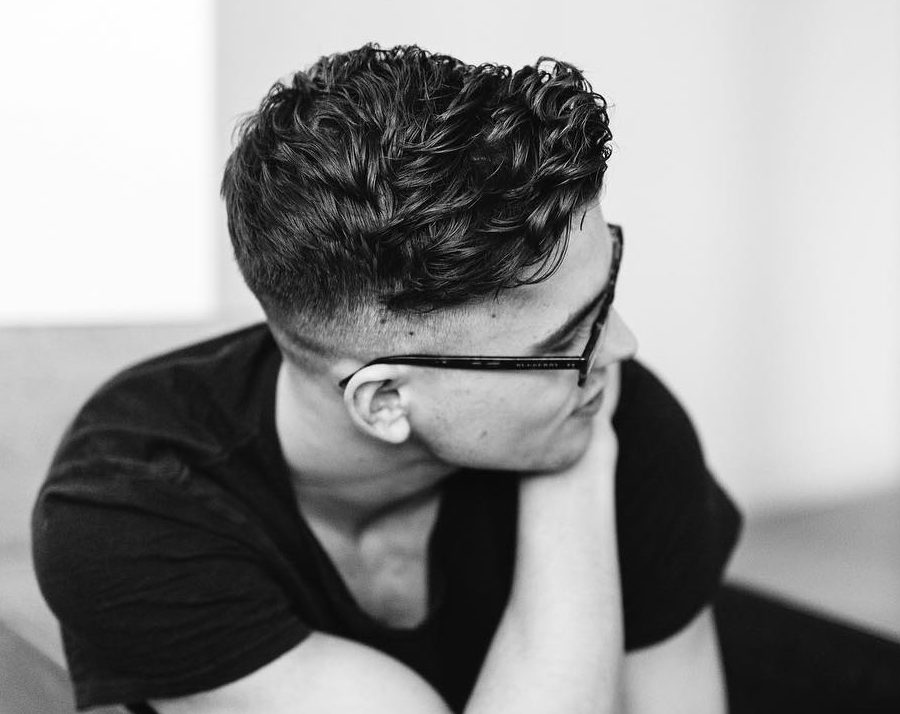 Wavy hairstyle for men in medium length with a low fade